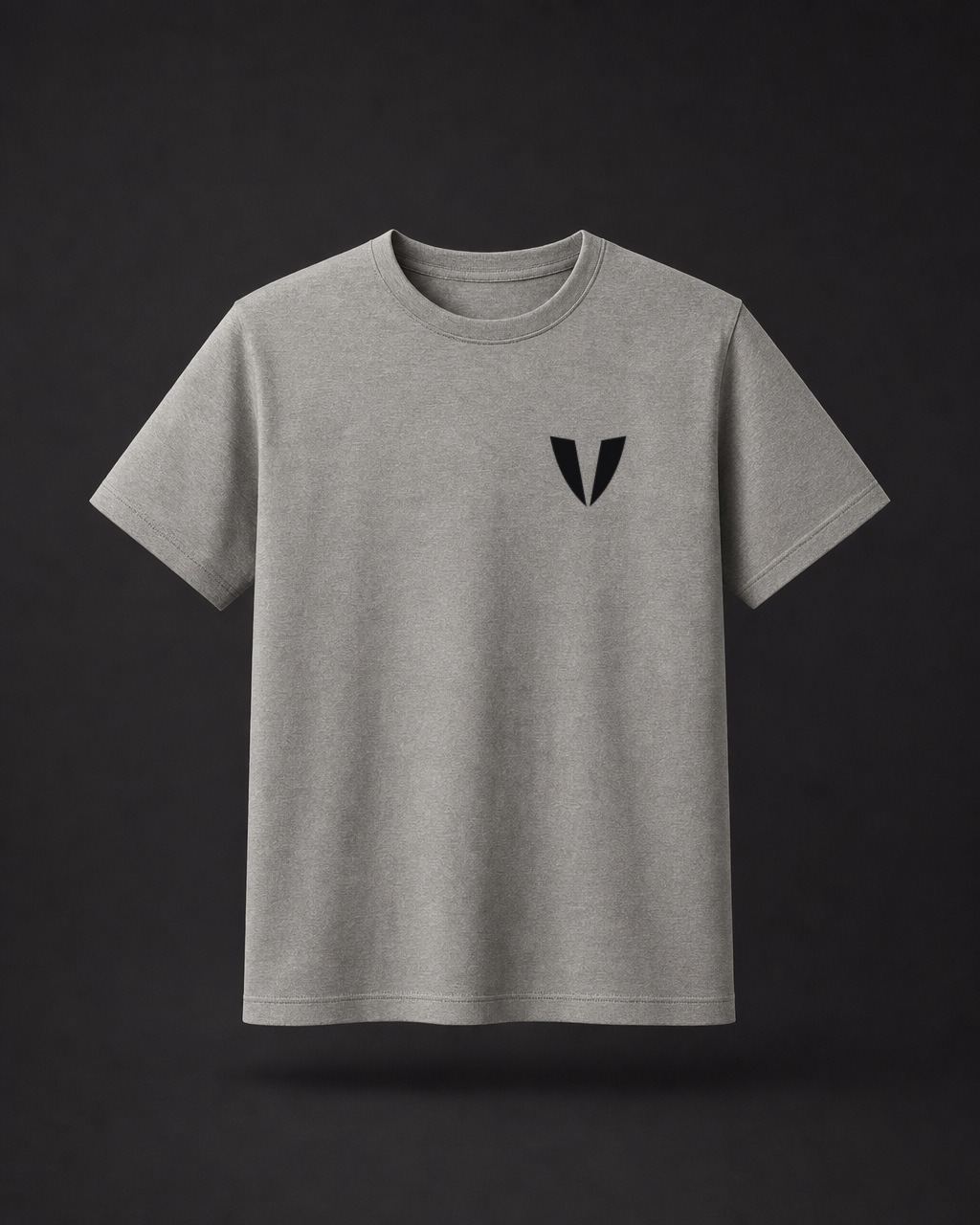 Frente de una camiseta gris con una V negra pequeña en el pecho izquierdo.